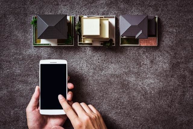 家の模型とスマートフォン