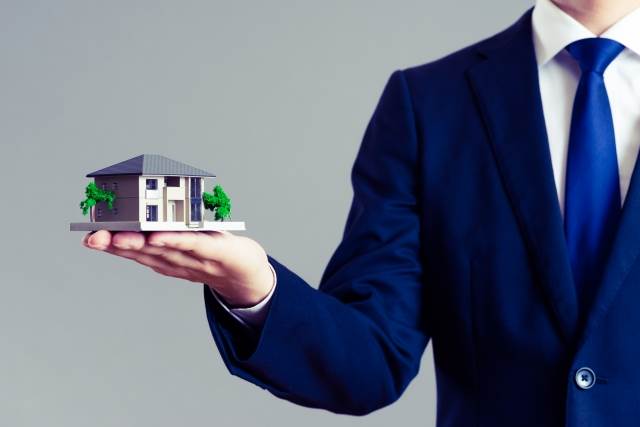 右手で家の模型を持つ男性