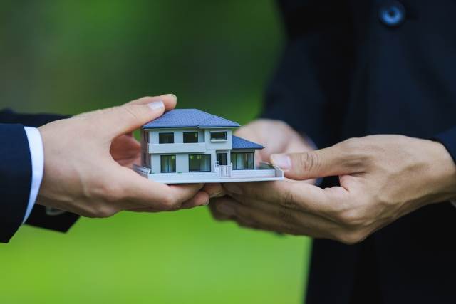 家の模型を手渡す男性